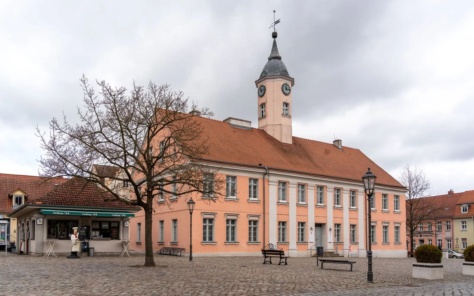 Brandenburg town hall in a small European town center against a cloudy sky.
