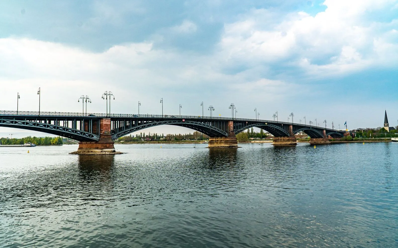 Steel arch bridge over the Rhine in Mainz, Germany under a cloudy sky.