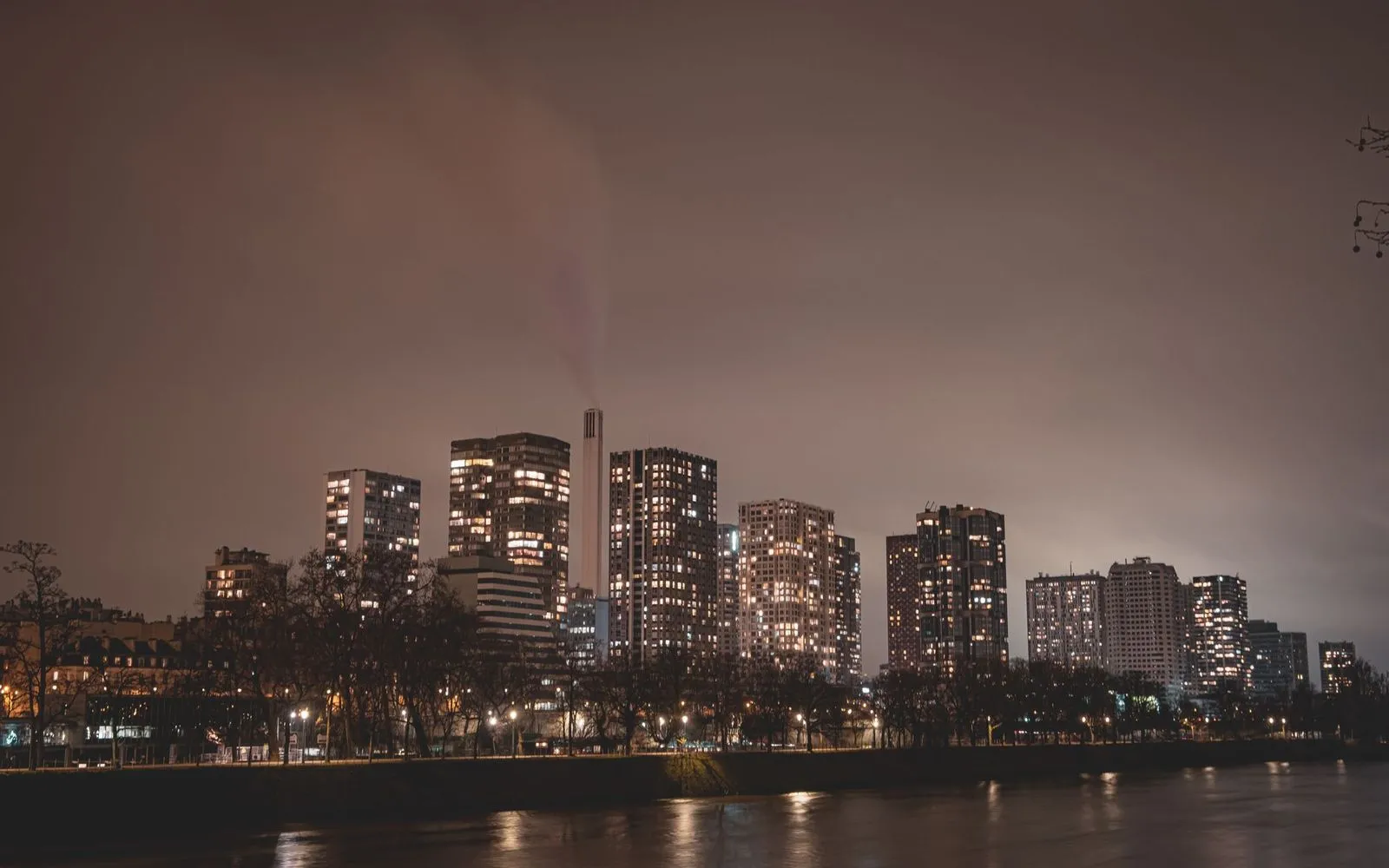 Captivating nighttime view of Paris skyline with illuminated skyscrapers along the river.